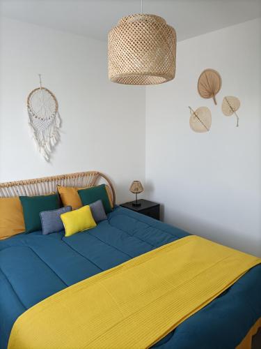 un lit avec une couverture bleue et jaune dessus dans l'établissement L'hippocampe, à Gruissan