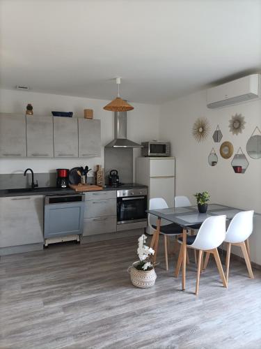 une cuisine avec une table et des chaises dans une pièce dans l'établissement L'hippocampe, à Gruissan