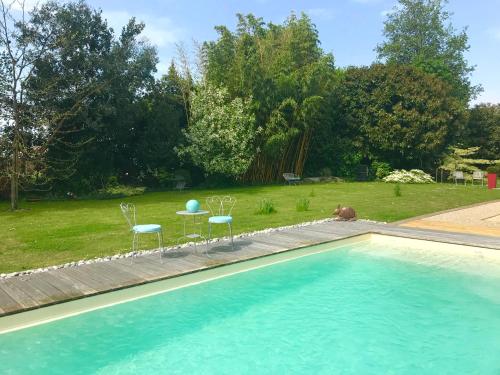 une piscine avec deux chaises et une table dans l'établissement LE CLOS DE LA HOURSERIE, à Pornic