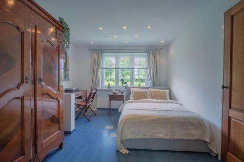 een slaapkamer met een bed, een bureau en een raam bij Countryside - experience in Koewacht