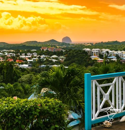 a view of a city at sunset with a blue bench at Villa Marissea in Rivière-Salée