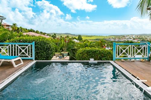 a swimming pool with a wooden deck and a blue bench at Villa Marissea in Rivière-Salée