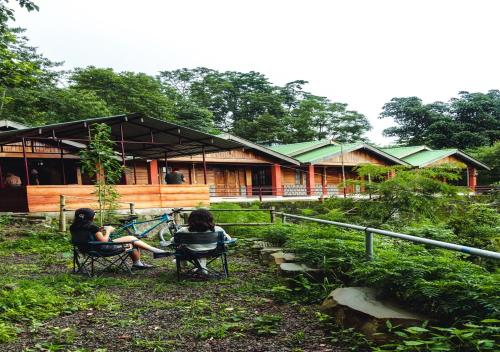three people sitting in chairs in front of a building at Camp David, Kigwema in Kohīma