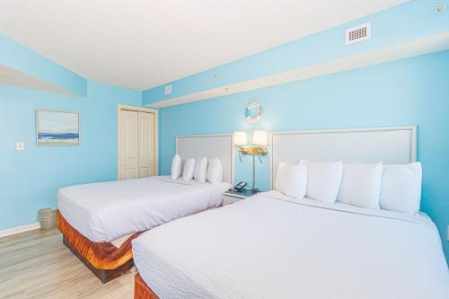 two beds in a hotel room with blue walls at 1 Bedroom Suite with City and Partial Ocean Views- Bay View Resort 702 in Myrtle Beach