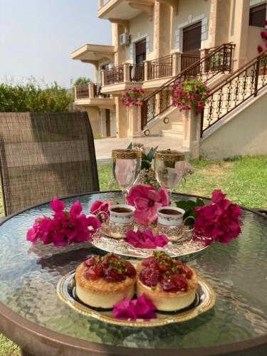 a table with two plates of food and glasses and flowers at Elxis Luxury Resort in Nea Vrasna