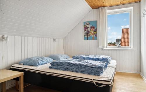 a bed with blue pillows in a room with a window at Beautiful Home In rum Djurs With Kitchen in Nimtofte