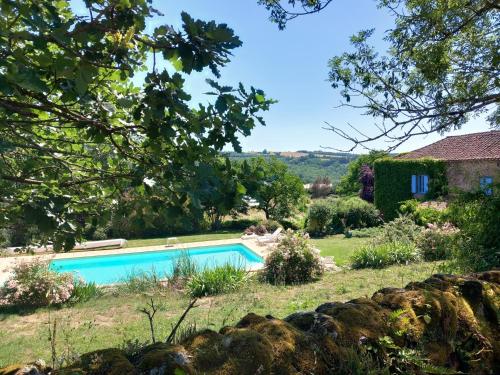a swimming pool in a garden with a house at Gite Les Volets Bleus du Segur in Le Ségur-Suech