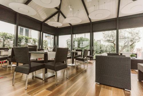a dining room with tables and chairs and windows at Palazzo Bezzi Hotel in Ravenna