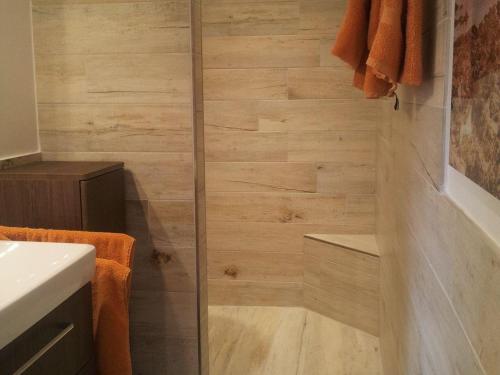 a shower in a bathroom with a wooden wall at Krohn in Großpösna