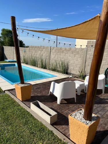 a swimming pool with chairs and a table and a umbrella at Alquiler x dia in Libertador San Martín