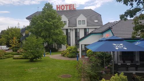 een hotel met een blauwe paraplu ervoor bij Hotel Restaurant La Tour Romaine - Haguenau - Strasbourg Nord in Schweighouse-sur-Moder