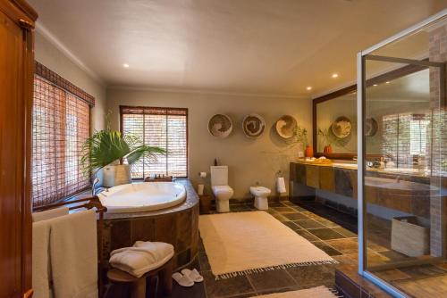 a bathroom with a tub and a toilet and a sink at Simbavati River Sands in Timbavati Game Reserve