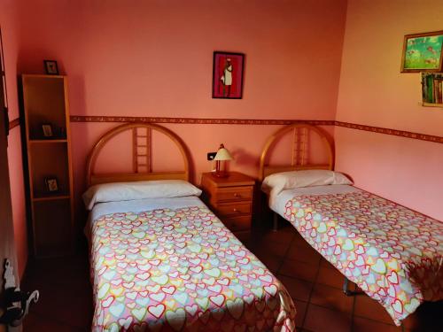 two beds in a room with pink walls at La Celestina in Candeleda