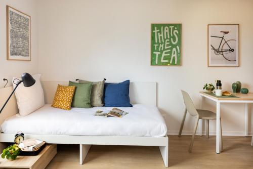 - un lit blanc dans une chambre avec une table et un bureau dans l'établissement Apparteo Montpellier, à Montpellier