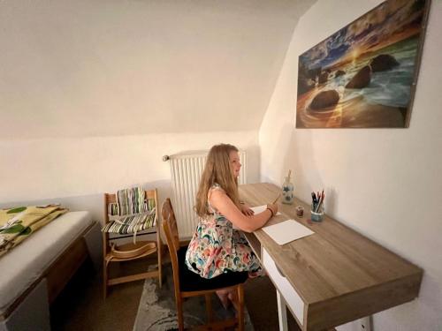 a woman sitting at a table in a room at Haus Gruber - Valentina & Gabriel in der Waldheimat in Krieglach
