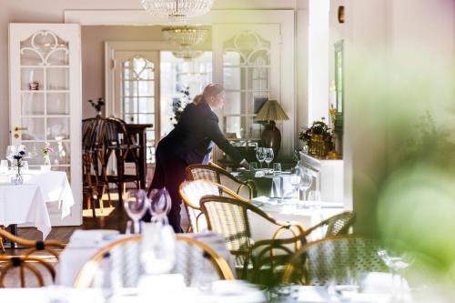 a woman is setting a table in a restaurant at Stella Maris in Svendborg