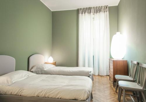 Zimmer mit 3 Betten, einem Stuhl und einem Fenster in der Unterkunft Margreth Apartment in Mailand
