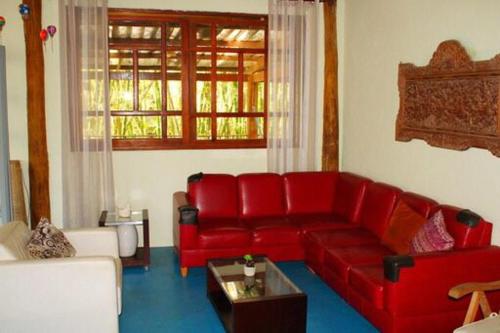 a living room with a red couch and a table at Portal do Sabiá Maresias in Maresias