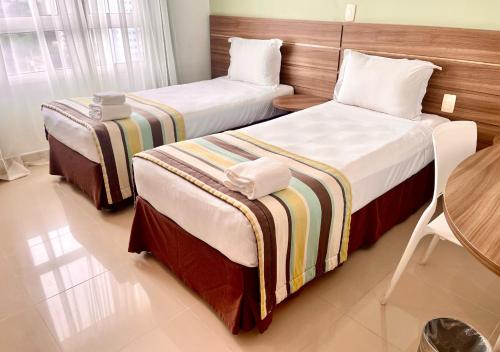 a hotel room with two beds and a table at Express Vieiralves in Manaus