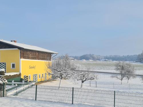 a yellow building with a fence in the snow at Landgasthof Entenwirt Tarsdorf in Tarsdorf