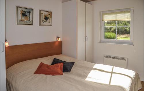 a bedroom with a bed with an orange pillow on it at 4 Bedroom Cozy Home In Nrre Nebel in Lønne Hede