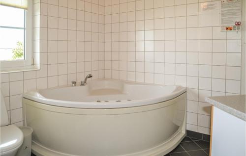 a white bath tub in a bathroom with a toilet at 4 Bedroom Cozy Home In Nrre Nebel in Lønne Hede