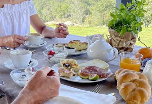 eine Person, die an einem Tisch mit Frühstücksspeisen sitzt in der Unterkunft Poggio Belvento in Suvereto