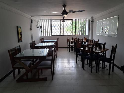un comedor con mesas y sillas y una ventana en Hotel Exito Barranquilla, en Barranquilla