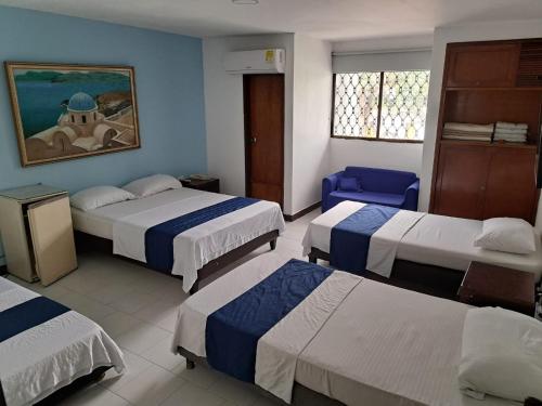 a hotel room with three beds and a blue wall at Hotel Exito Barranquilla in Barranquilla