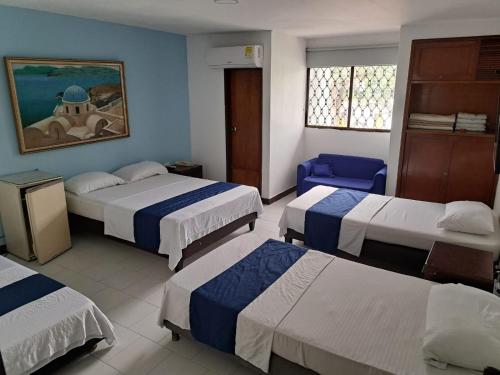 Habitación de hotel con 3 camas y pared azul en Hotel Exito Barranquilla, en Barranquilla