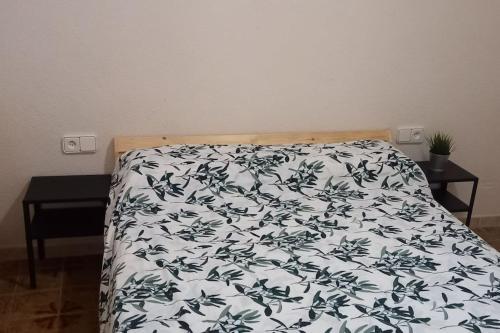 a bed with a black and white blanket on it at Acogedor apartamento a 10min de PortAventura. in Tarragona
