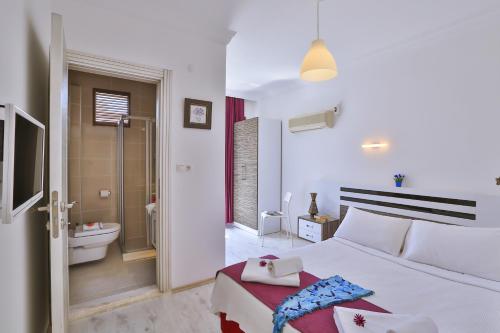 a white bedroom with a bed and a bathroom at Antiphellos Pension Küçükçakıl in Kas