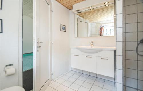 ein Bad mit einem Waschbecken und einem Spiegel in der Unterkunft Pet Friendly Home In Blvand With Sauna in Blåvand