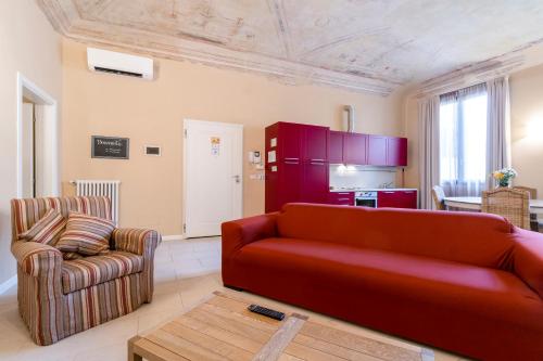 a living room with a red couch and a kitchen at Broccaindosso 33 - Appartamento nel Centro Storico in Bologna