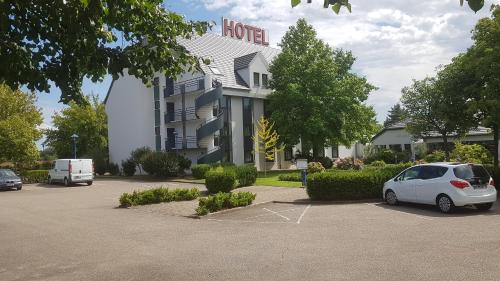 une voiture blanche garée dans un parking en face d'un hôtel dans l'établissement Hotel Restaurant La Tour Romaine - Haguenau - Strasbourg Nord, à Schweighouse-sur-Moder