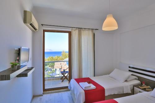 a hotel room with two beds and a large window at Antiphellos Pension Küçükçakıl in Kaş