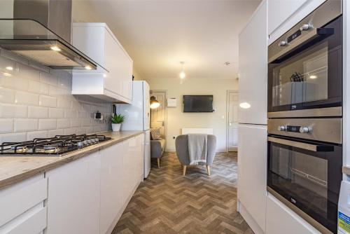 a kitchen with white cabinets and a stove top oven at Stay @ Baker Street Derby in Derby