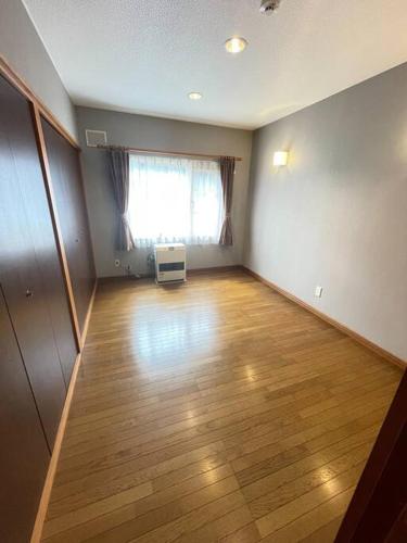 an empty room with a hard wood floor and a window at コテージR 広々空間と自然豊かなエリアでRelaxステイ バーベキューセットあり4名様まで同一料金 in Shiraoi