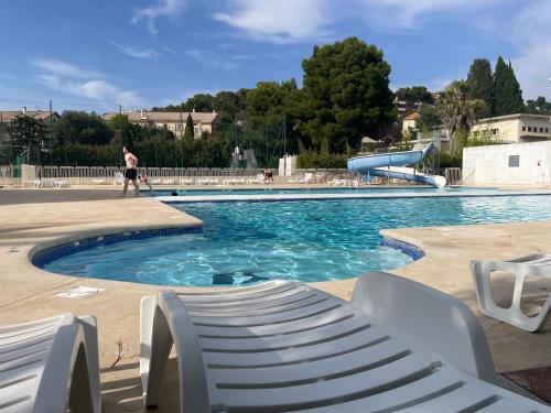 - une piscine avec un toboggan et un homme qui s'y promène dans l'établissement Appartement plage piscine et tennis inclus, à La Londe-les-Maures