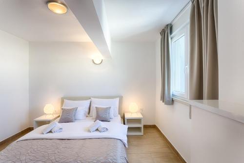 a bedroom with a bed with white sheets and a window at Adriatic Queen Residence in Split