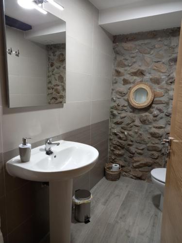 a bathroom with a sink and a stone wall at Hotel Rural Virgen del Carmen in Molinaseca