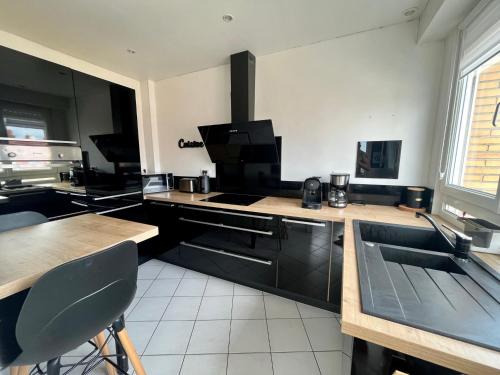 une cuisine avec des placards noirs et un comptoir avec un évier dans l'établissement Appartement 6/8 pers Plage à 10min NETFLIX, à Dunkerque