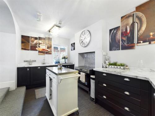 a kitchen with black cabinets and a clock on the wall at Montague House in Ross on Wye