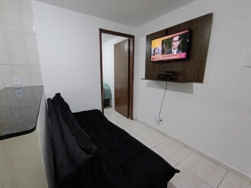 Habitación con sofá y TV en la pared. en Apartamento Aconchegante, en Brasilia