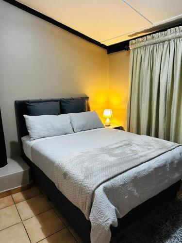 a bedroom with a large bed with a window at A Cozy Secure 2-Bed Apartment with a lovely garden in Gaborone