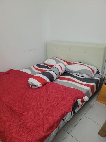 a bed with a red and white blanket on it at P'RESIDENSI HOLIDAY APARTMENT in Puchong