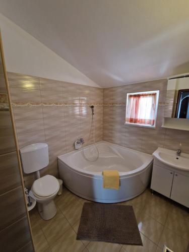 a bathroom with a tub and a toilet and a sink at Villa Luka in Barbariga
