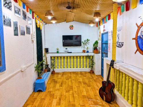 a room with a guitar and a tv in it at Awaara Backpackers Hostel, Alibag in Alībāg