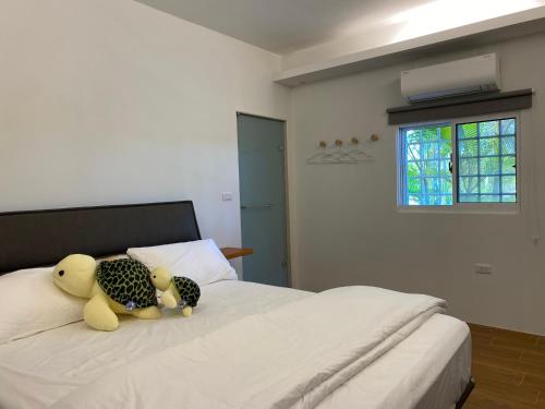 dos animales de peluche sentados encima de una cama en Lily Garden Homestay en Yilan City