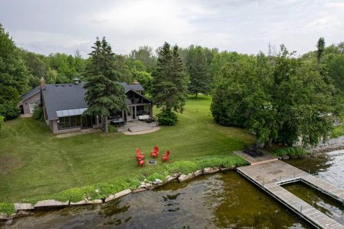 an aerial view of a house with two people standing on a lawn by a river at Waterfront - Kawartha Lakes in Kawartha Lakes